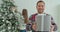 Happy man offering amazing handmade holiday present on Christmas. Beautiful woman decorates a Christmas tree in the