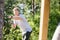 Happy Man Pulling Rope Attached To Wooden Structure In Forest