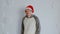 Happy man in santa hat on background of white patterned wall. Young male in warm clothes and christmas hat looking at