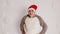 Happy man in santa hat on background of white patterned wall. Young male in warm clothes and christmas hat looking at