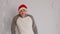 Happy man in santa hat dancing on background of white patterned wall. Joyful male in festive mood looking at camera and