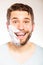 Happy man with shaving cream foam on half of face.