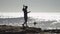 Happy man on is shooting a marvelous landscape on video while dancing on a seashore