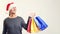 Happy man shopper holding shopping bags. Man wears Santa hat. Christmas time, sale, shopping. It is time for buying christmas