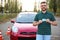 Happy man showing driving license near new car