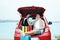 Happy man sitting in car trunk with suitcases