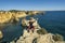 Happy man sitting on the top of cliffs at Marinha beach, Algarve, Portugal