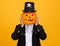 Happy man in a skeleton costume covers head with pumpkin and celebrates Halloween on yellow background