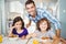 Happy man standing by children having breakfast