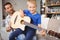 Happy man teaching guitar to son at home