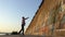 Happy man throws a ball on a river bank wall in slo-mo