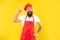 Happy man in toque and apron got idea keeping finger raised yellow background, chef