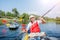 Happy man with two kids enjoying kayak ride on beautiful river. Father with little boy and teenager girl kayaking on hot