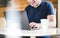 Happy man using laptop with take away coffee cup on table.