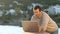 Happy man video calling on laptop on vacation on the beach