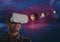 happy man in VR headset looking at 3D planets against galaxy background