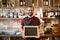 Happy man or waiter with chalkboard banner at bar