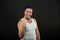 Happy man with winner gesture. Macho smile in casual vest and hat on dark background. Sportsman with bristle on smiling