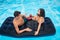 Happy man and woman drinking cocktails on a mattress in the pool enjoying each other and a holiday, top view