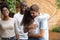 Happy man and woman greeting hugging at multi-ethnic friends meeting