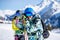 Happy man and woman snowboarders standing on snow resort against backdrop of mountain.