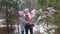 A happy married couple embrace each other and a child while among the snow-covered fir trees in the winter forest