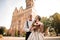 Happy married couple with a wedding bouquet standing in background of beautiful building