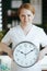 happy massage therapist woman in massage cabinet with clock
