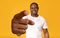 Happy mature African American guy pointing at camera with big hand over orange studio background
