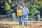 Happy mature couple in autumn park in the embrace walk on the fallen maple leaves