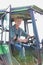 Happy mature farmer driving tractor in field