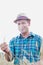 Happy mature farmer wearing hat while examining wheat crop in field