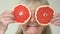 Happy mature female holding grapefruit slices front of eyes, vitamins nutrition