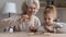 Happy mature grandmother and little granddaughter play chess