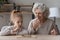 Happy mature grandmother and little granddaughter playing wooden board game