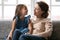 Happy mature grandmother and small granddaughter relax on sofa