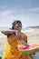 Happy mature Indian woman cutting watermelon at Vagator Beach