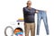 Happy mature man holding a pair of jeans in front of a washing machine