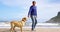 Happy mature man playing with dog on the beach