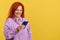 Happy mature redheaded woman smiling while using the mobile