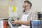 Happy mature sales clerk reading instructions paint can in hardware store