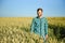 Happy mature technician checking the growth of the wheat for a quality control in a cereal field in summer