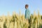 Happy mature technician checking the growth of the wheat for a quality control in a cereal field in summer