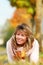 Happy mature woman with autumn leaves lying in the meadow