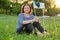 Happy mature woman gardener resting sitting on grass with cup of tea