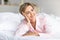 Happy mature woman looking away and thinking in bed