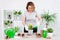 Happy mature woman planting spring flowers in pots at home