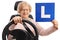 Happy mature woman sitting in a car seat and holding an L-sign