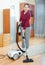Happy mature woman vacuuming with vacuum cleaner