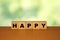 HAPPY message word on a wooden desk on cube blocks with a green nature